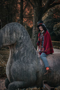 Portrait of smiling man cosplaying mad hatter sitting on horse statue