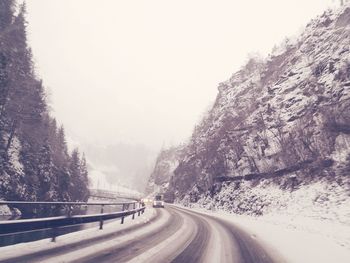 Road amidst snow covered mountains against clear sky