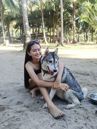 Portrait of young woman smiling while sitting on tree