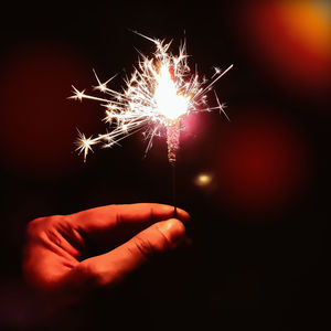 Close-up of hand holding sparkler at night