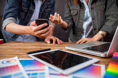Midsection of woman using mobile phone on table