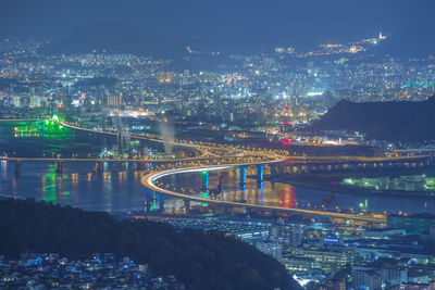 High angle view of illuminated bridge over river and buildings at night