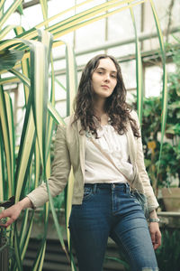 Portrait of young woman standing in greenhouse