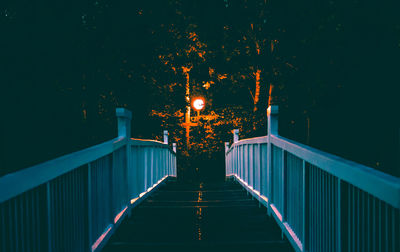 Illuminated street light on footbridge