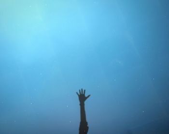 Low angle view of hand against blue water
