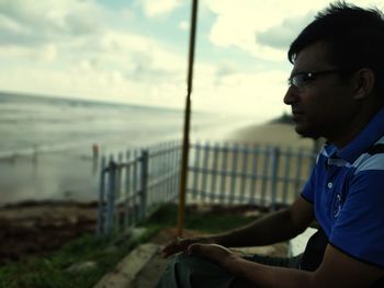 Side view of young man looking away against sea