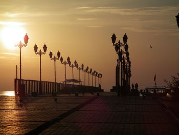 Statue of people in sea at sunset