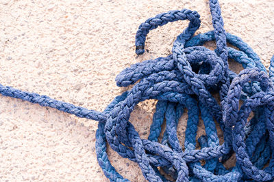 Close-up of rope tied up against blue wall