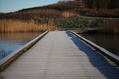 Boardwalk by lake against sky