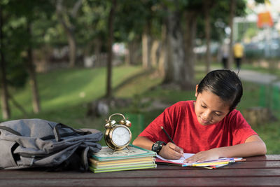 Boy studying on table in park