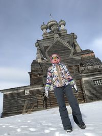 Low angle view of person standing on snow covered building