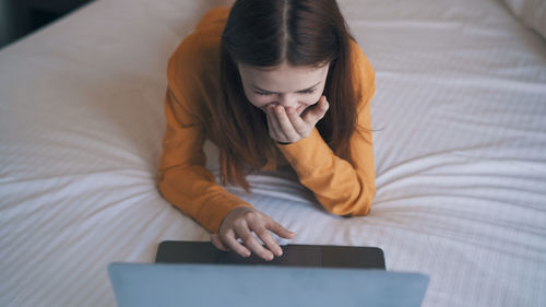 High angle view of woman using laptop while lying on bed at home