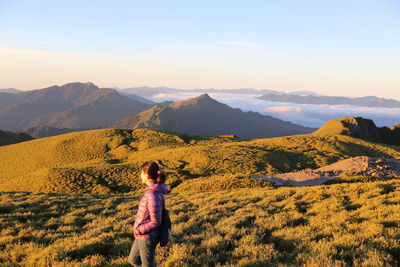 Rear view of woman looking at mountains against sky