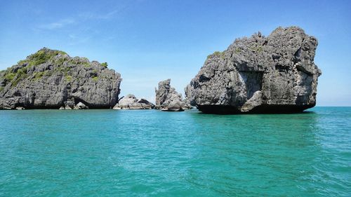 Scenic view of rocks in sea against blue sky