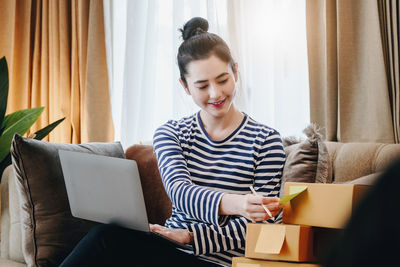 Young woman using laptop while sitting on sofa at home