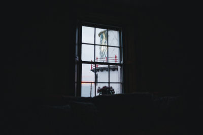 Lighthouse seen through window of dark building