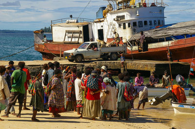 People at beach against boats in sea