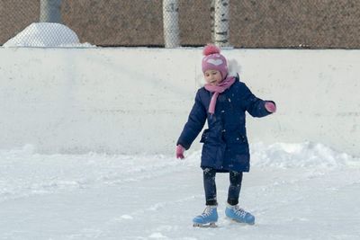 Full length of smiling girl ice skating on snow field