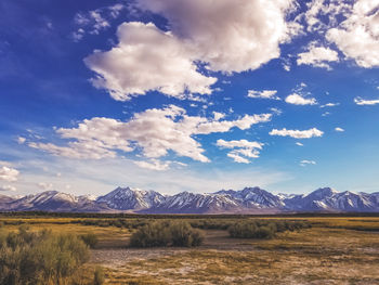 Owens river runs though arid plains against sierra nevada mountains and dramatic sky