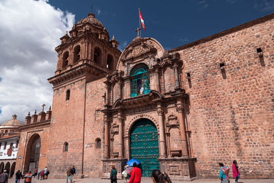 Group of people outside historic building against sky