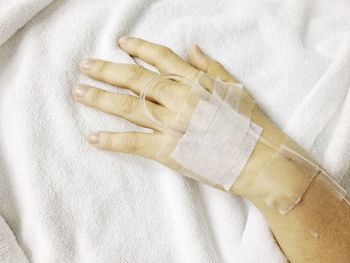 Close-up of patient hand with injection lying on hospital bed