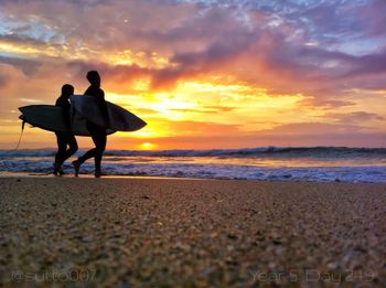 Silhouette of people on beach at sunset