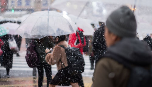 People with umbrella walking on road in city during winter