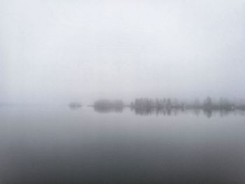 Scenic view of lake against sky at foggy weather