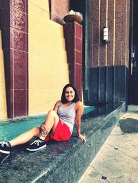 Portrait of happy mid adult woman sitting by fountain