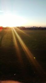 Scenic view of grassy field against sky at sunset