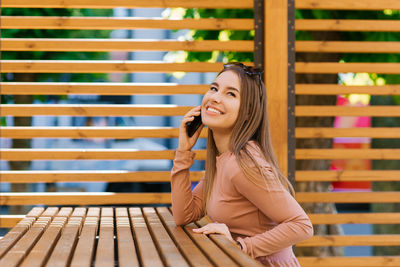 Young beautiful woman uses a mobile phone in a modern eco-friendly cafe.