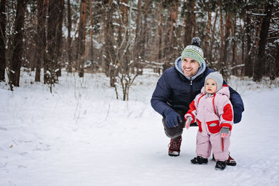 Outdoor portrait of young father and baby girl daughter in winter nature background. raising girls