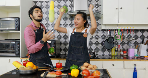 Happy friends standing in kitchen at home