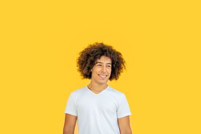 Portrait of young woman against yellow background