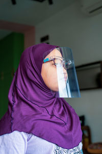 Close-up of woman wearing face shield at home