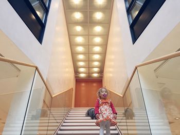 Low angle view of siblings on steps at hotel