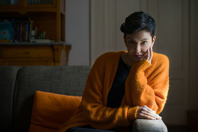 Portrait of smiling young woman sitting on sofa at home