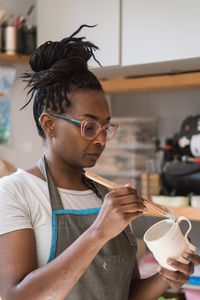 Female ceramic artist glazing a cup