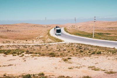 Car on road amidst land against sky