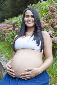 Young pregnant brazilian woman touching her belly in a garden person