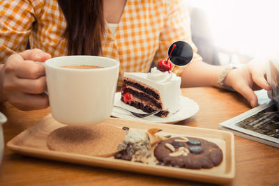 Midsection of man holding coffee cup on table