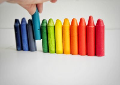 Cropped hand of person holding crayon on table