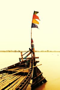 Low angle view of flag on sea against clear sky