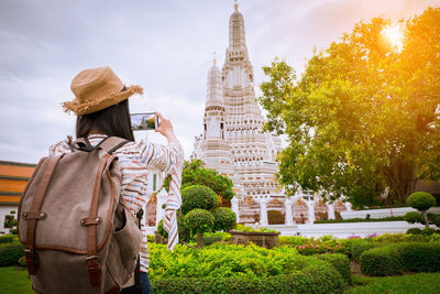 Rear view of man outside temple against sky