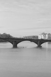 Bridge over river against sky in city