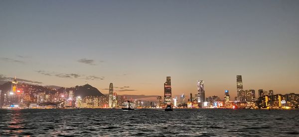 Illuminated buildings by city against sky at night