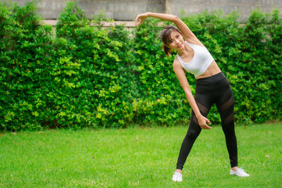 Full length of woman with arms raised on grass