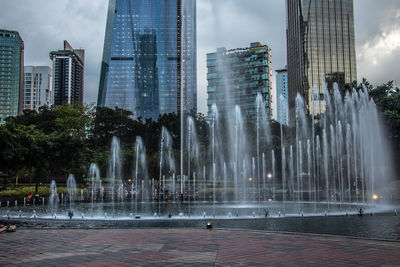 Fountain in city against sky