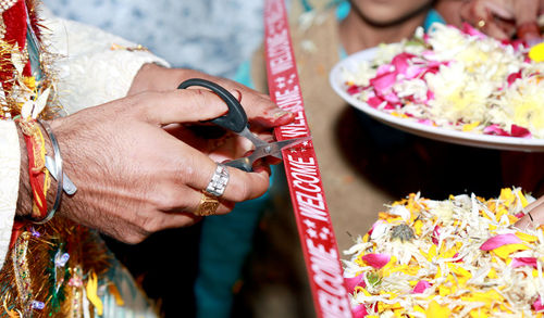 Midsection of groom cutting ribbon during wedding ceremony