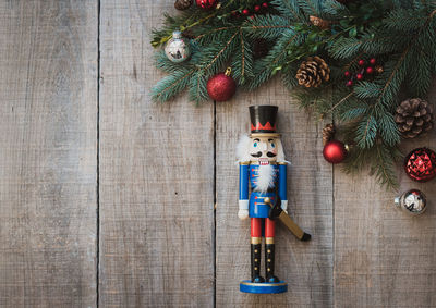 Christmas greenery, nutcracker and decorations against wood backdrop.